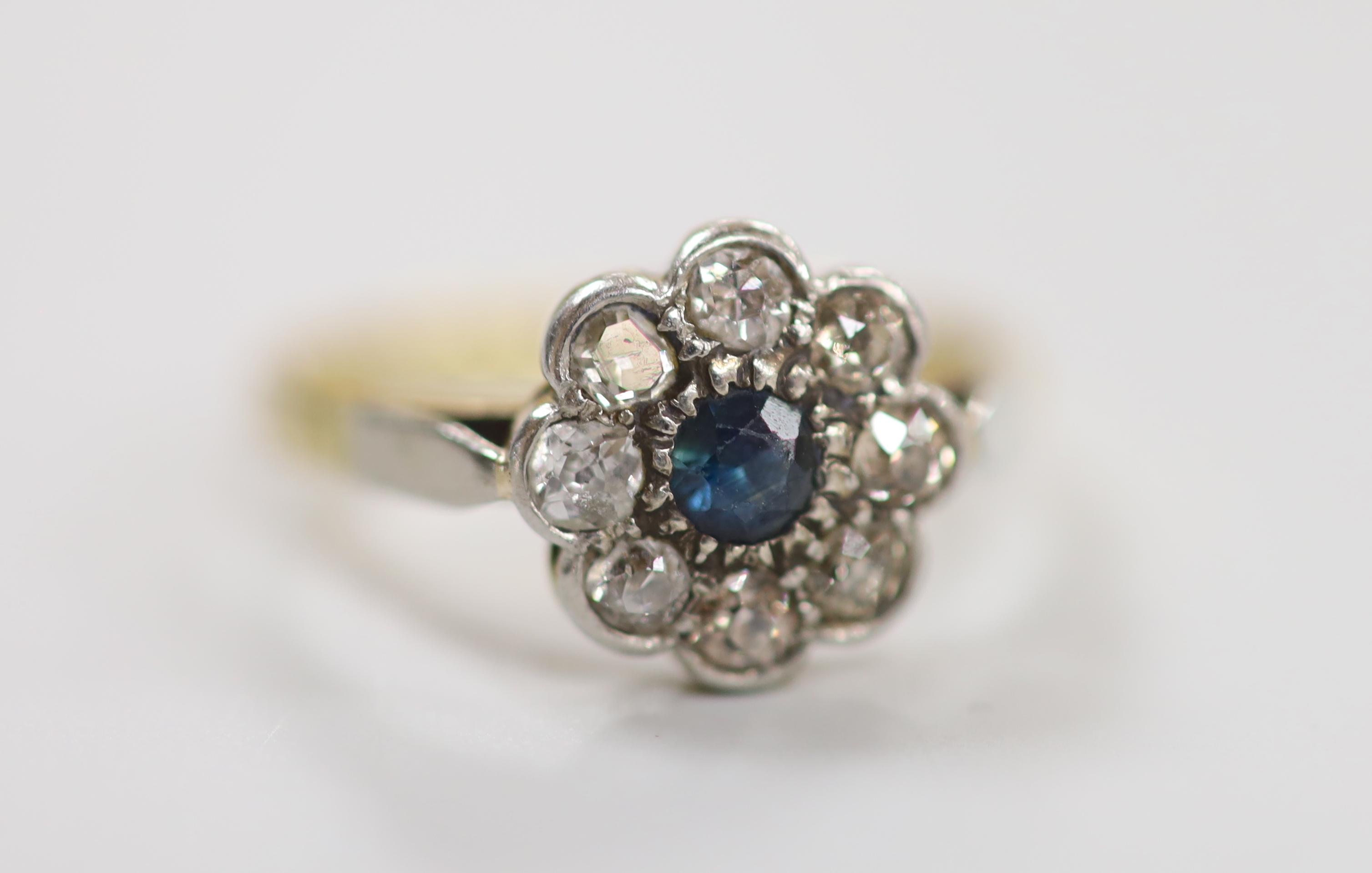 A 1940's yellow metal and plat, sapphire and diamond set circular cluster ring, size O, gross weight 3.8 grams.